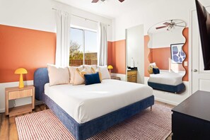 A bedroom with a bed, nightstands, a dresser, a mirror, and a ceiling fan. - Suncrest Pool Pickleball Theater (Scottsdale)