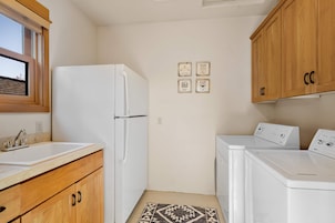 Cocina compacta con refrigerador, lavadora y armarios de madera.