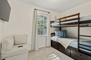 A bedroom with a bunk bed, a sofa, a window with curtains, and a television on the wall. - Near USC Downtown Fire Pit Dog Friendly (Columbia)