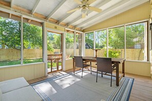 A covered patio with a table and chairs, large windows, and a ceiling fan. - Near USC Downtown Fire Pit Dog Friendly (Columbia)