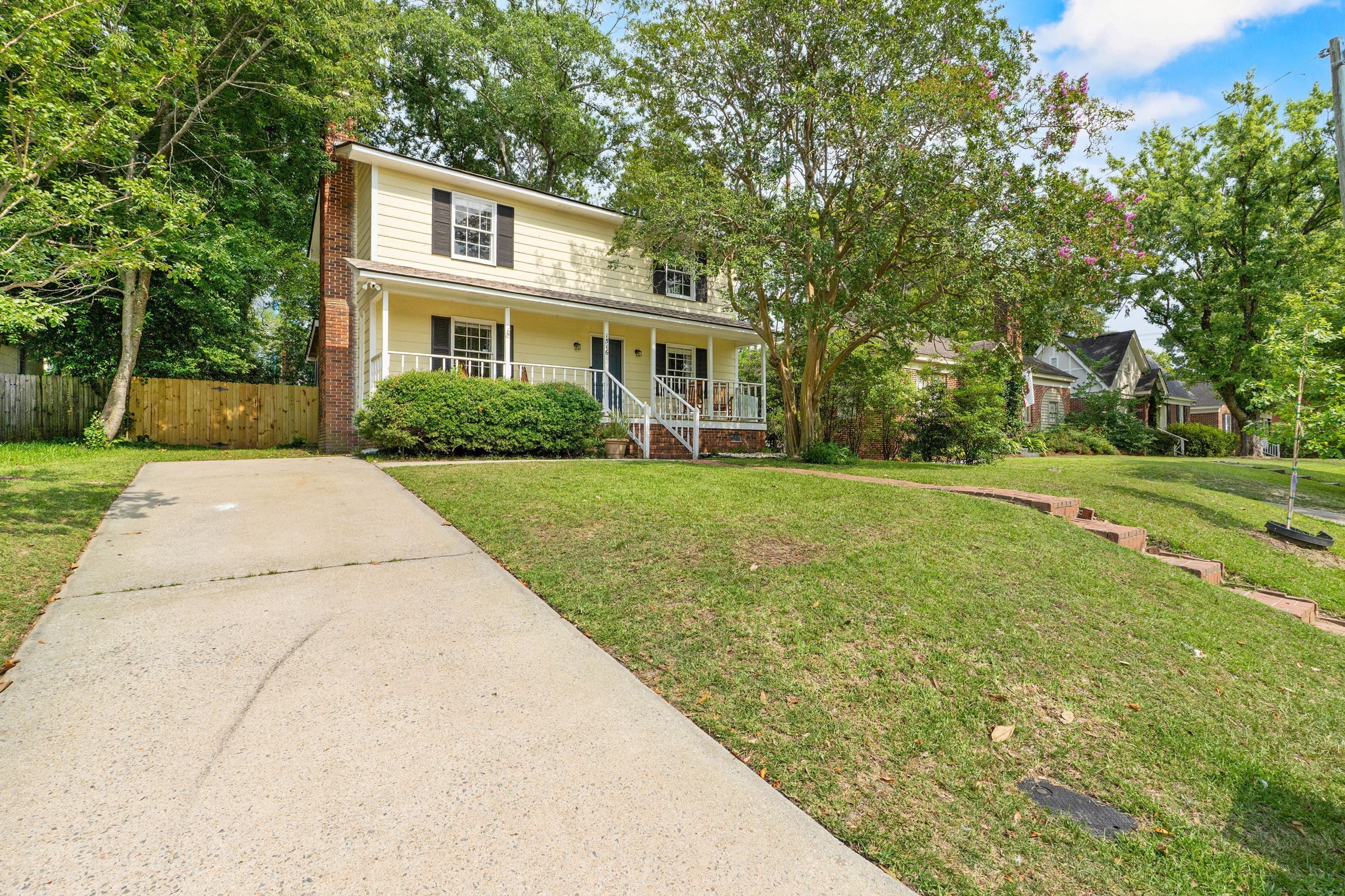 A two-story house with a front porch, a brick chimney, and a well-maintained lawn.