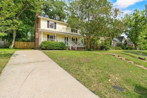 A two-story house with a front porch, a brick chimney, and a well-maintained lawn. - Near USC Downtown Fire Pit Dog Friendly (Columbia)