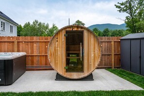 A hot tub in a wooden structure with a wooden fence and a house in the background. - Mountain Getaway Outdoor Games Sauna Hot tub (North Conway)