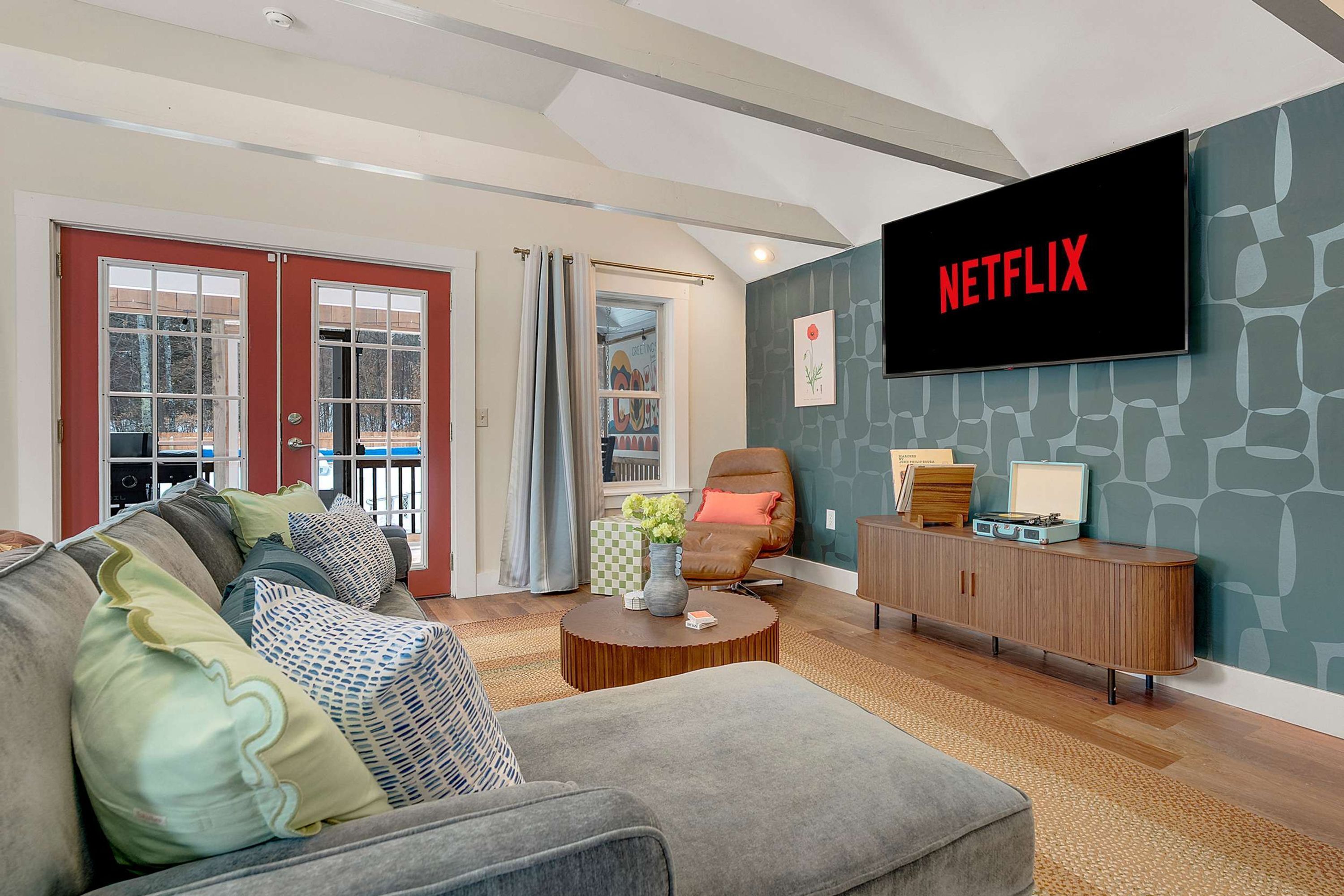 A modern living room with a sofa, armchair, coffee table, and a television mounted on the wall.