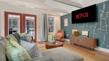 A modern living room with a sofa, armchair, coffee table, and a television mounted on the wall.