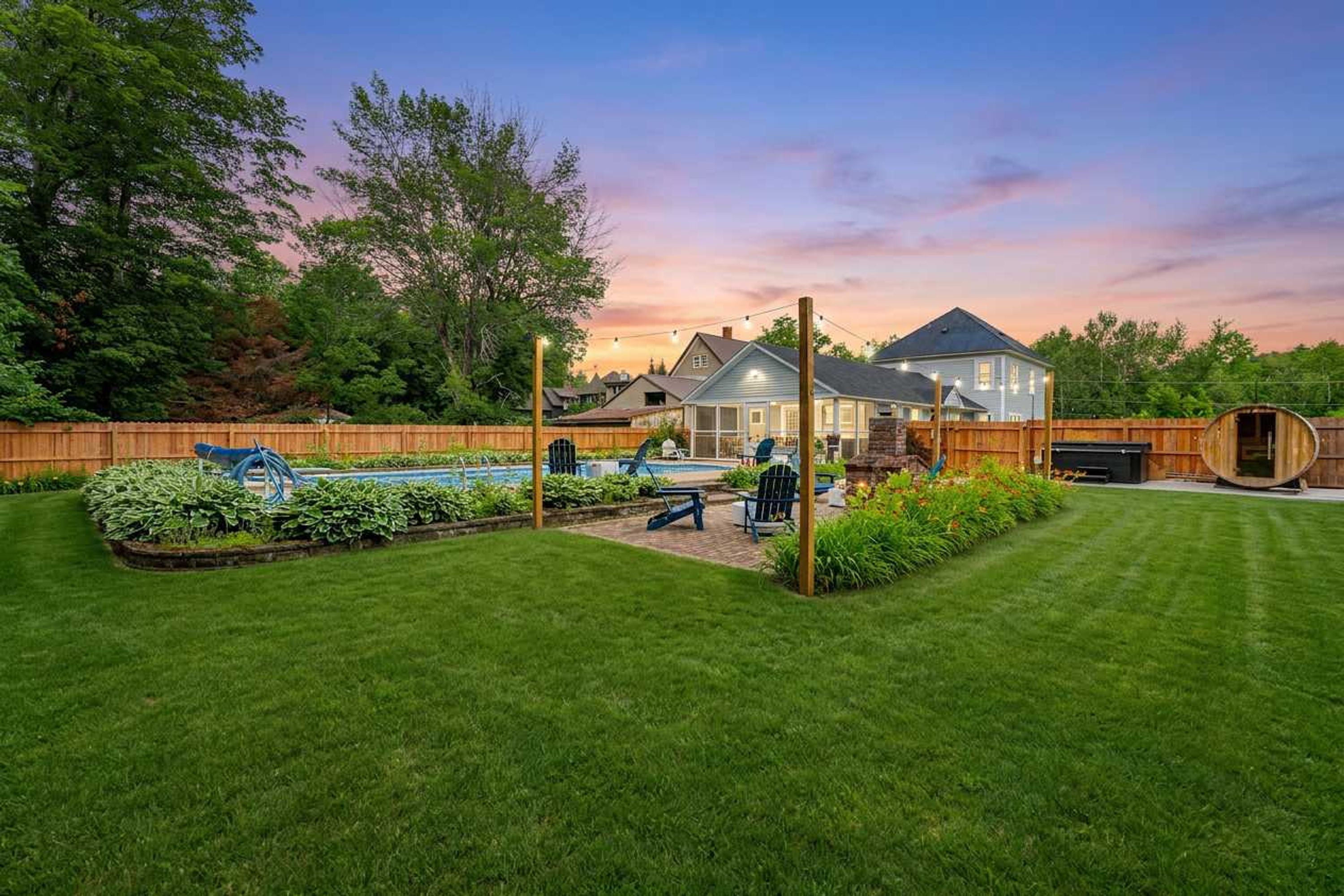 A residential backyard with a swimming pool, a barbecue area, and a wooden fence.