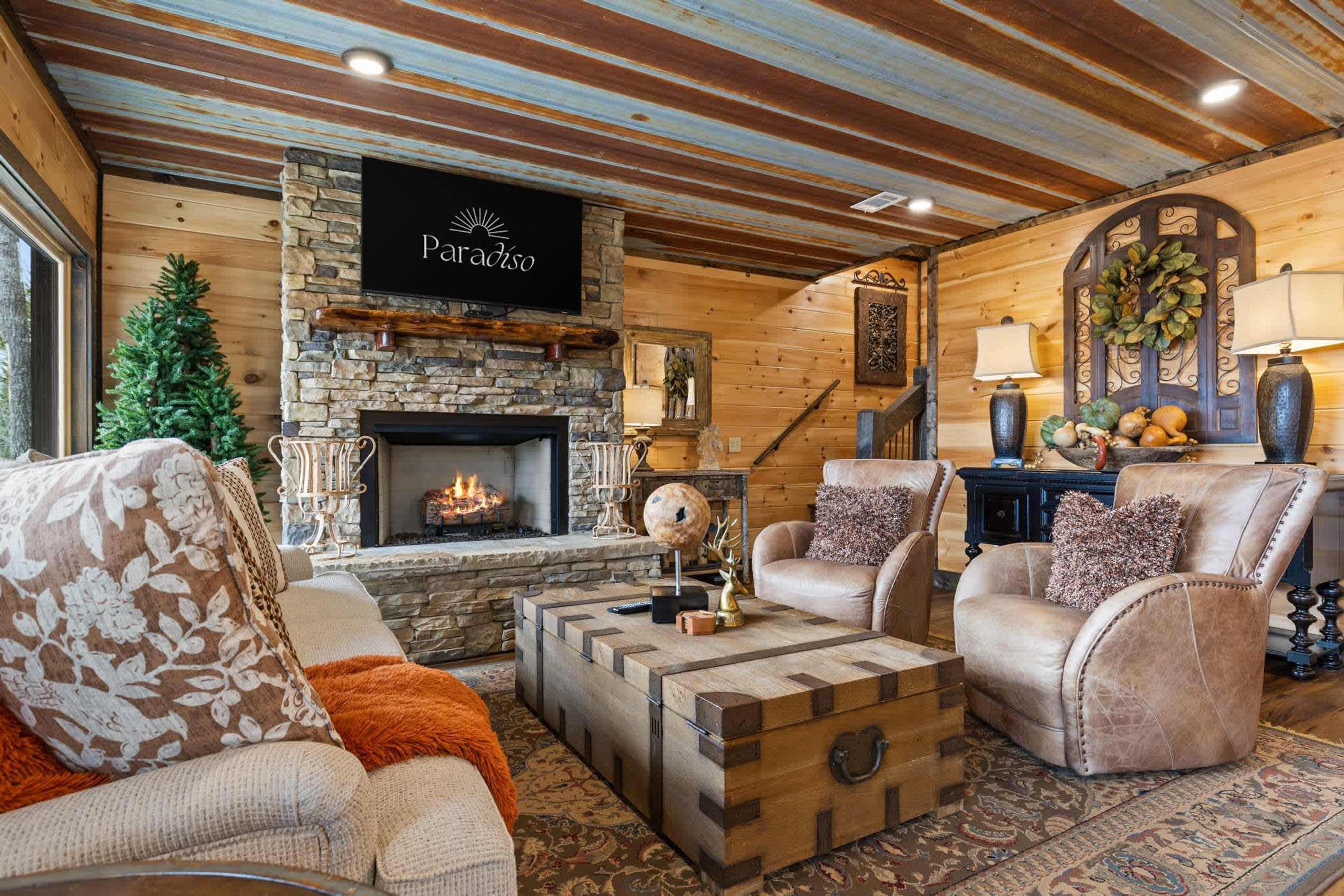 Un salon chaleureux avec une cheminée en pierre, des canapés en cuir et un plafond en bois rustique.