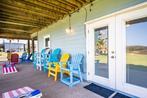 A covered porch with colorful Adirondack chairs and a small American flag table. - Coastal Casa-ocean Views Family Friendly 5BR (Port Aransas)