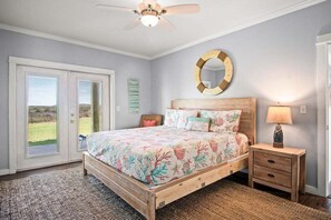 A bedroom with a bed, a nightstand, a mirror, and a ceiling fan. - Coastal Casa-ocean Views Family Friendly 5BR (Port Aransas)