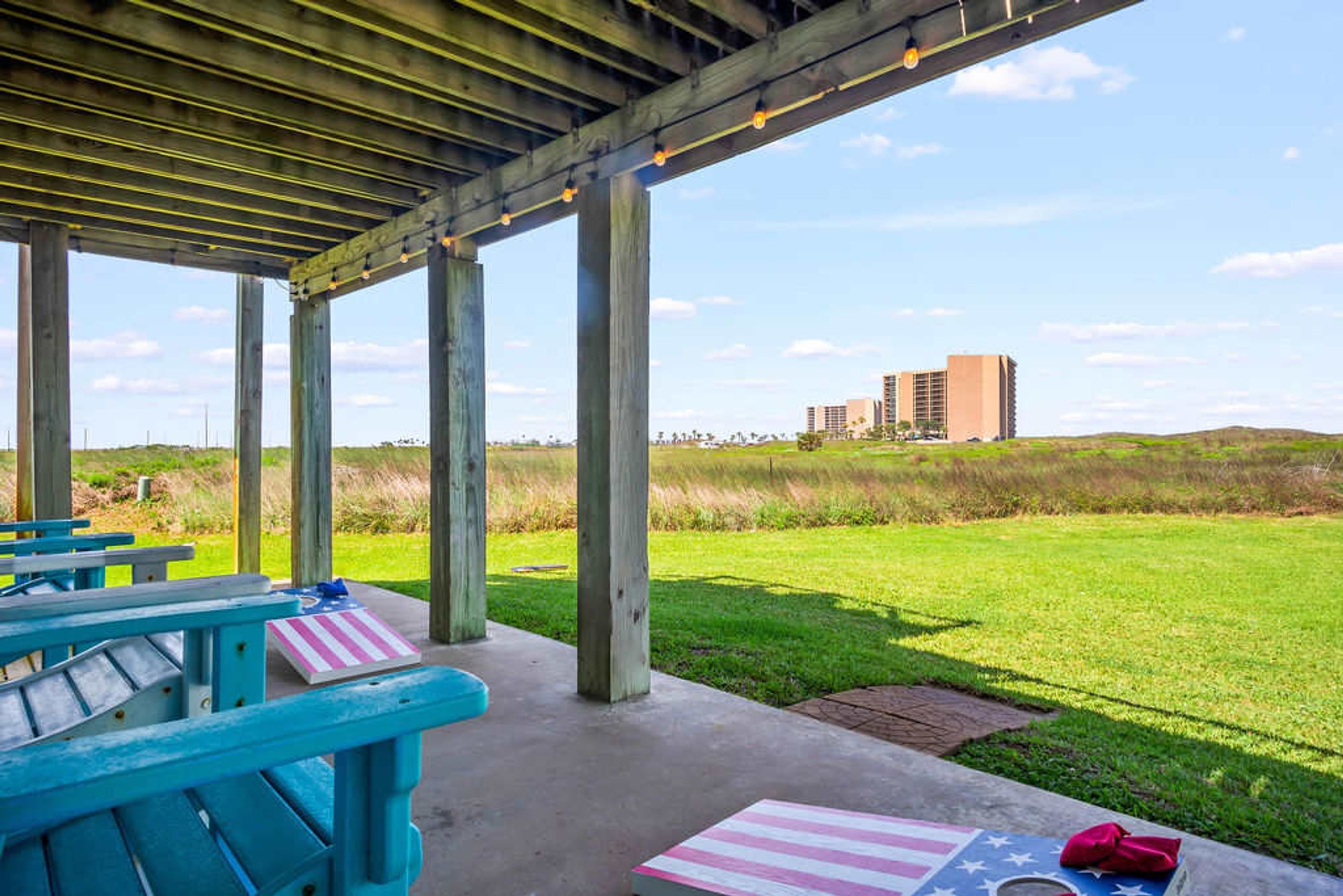 A covered outdoor area with picnic tables and a view of a grassy field and buildings in the distance.