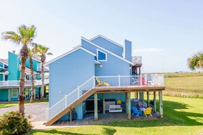 A two-story blue house with a covered porch and a small deck. - Coastal Casa-ocean Views Family Friendly 5BR (Port Aransas)