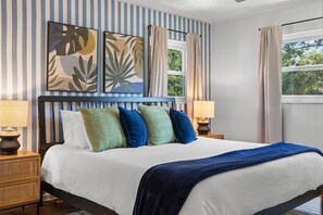 A bed with a blue headboard, white bedding, and multiple pillows in green, blue, and white. - 4 Minutes to Beach Pool Hot Tub Game Room (Seminole)