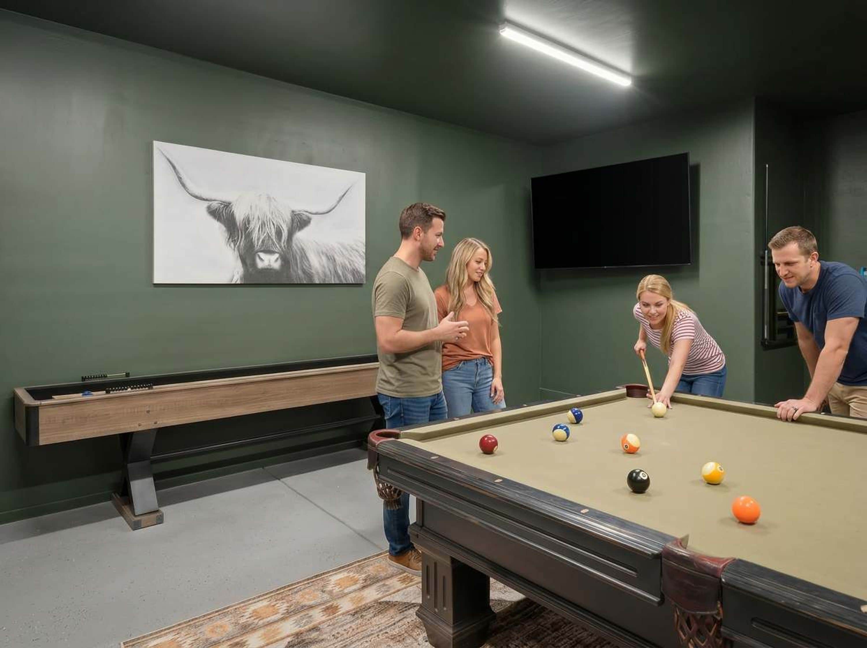 A pool table in a room with a green wall and a bull painting.