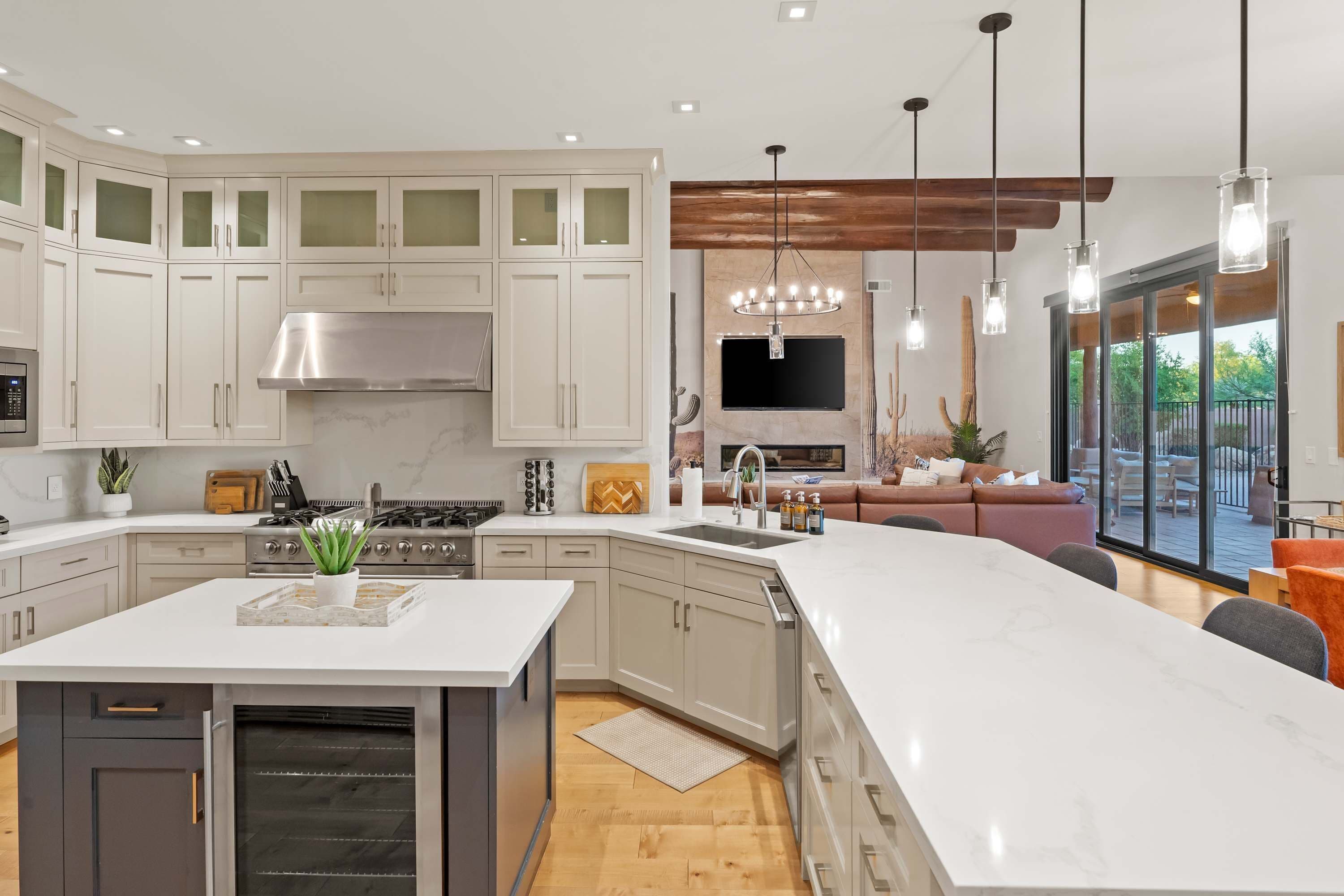 A modern kitchen with white cabinetry, a central island, and a dining area with a large window.