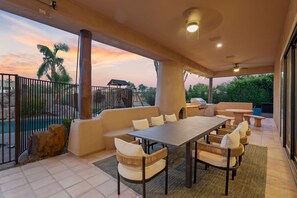 A covered outdoor patio with a pool, seating area, and a view of the sunset. - The Good Life Oasis Luxury 5BR Home Sleeps 16 (Glendale)