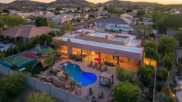 A residential property with a swimming pool, outdoor seating area, and a basketball court.