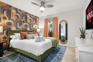 A modern hotel room with a large bed, a ceiling fan, a TV, and a view of the outdoors. - Soak Sizzle Score Pool Games More (San Antonio)