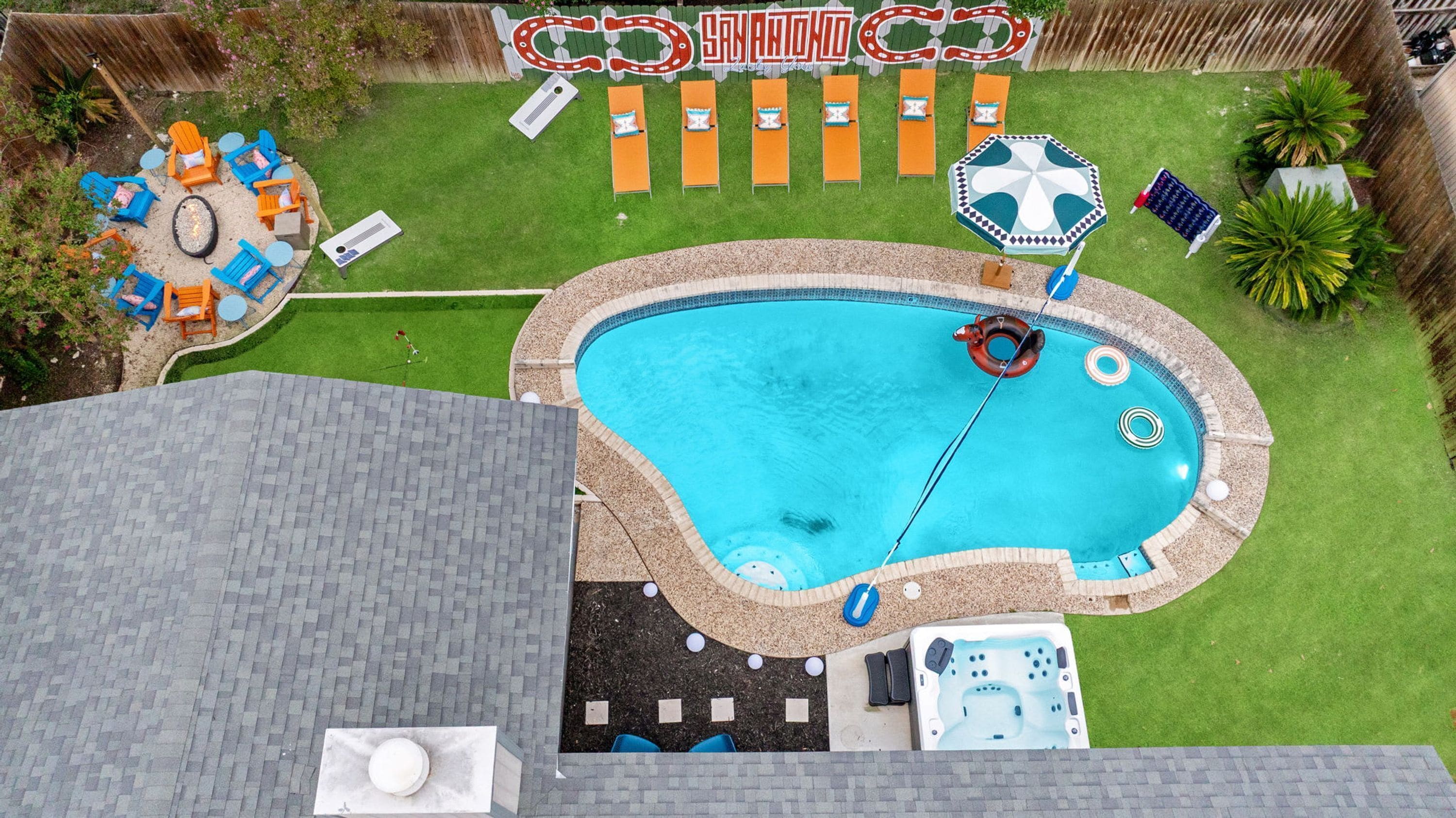 A backyard with a swimming pool, lounge chairs, and a hot tub.