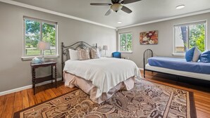 A bedroom with a bed, a desk, a chair, a ceiling fan, and a window. - The Live Oak Pickleball-hot Tub-dog Friendly (Fredericksburg)