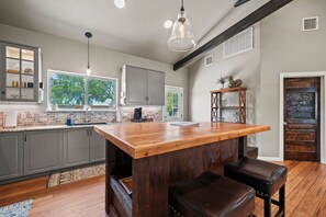Eine moderne Küche mit einer zentralen Kochinsel, grauen Schränken und einer Holzausziehtafel.