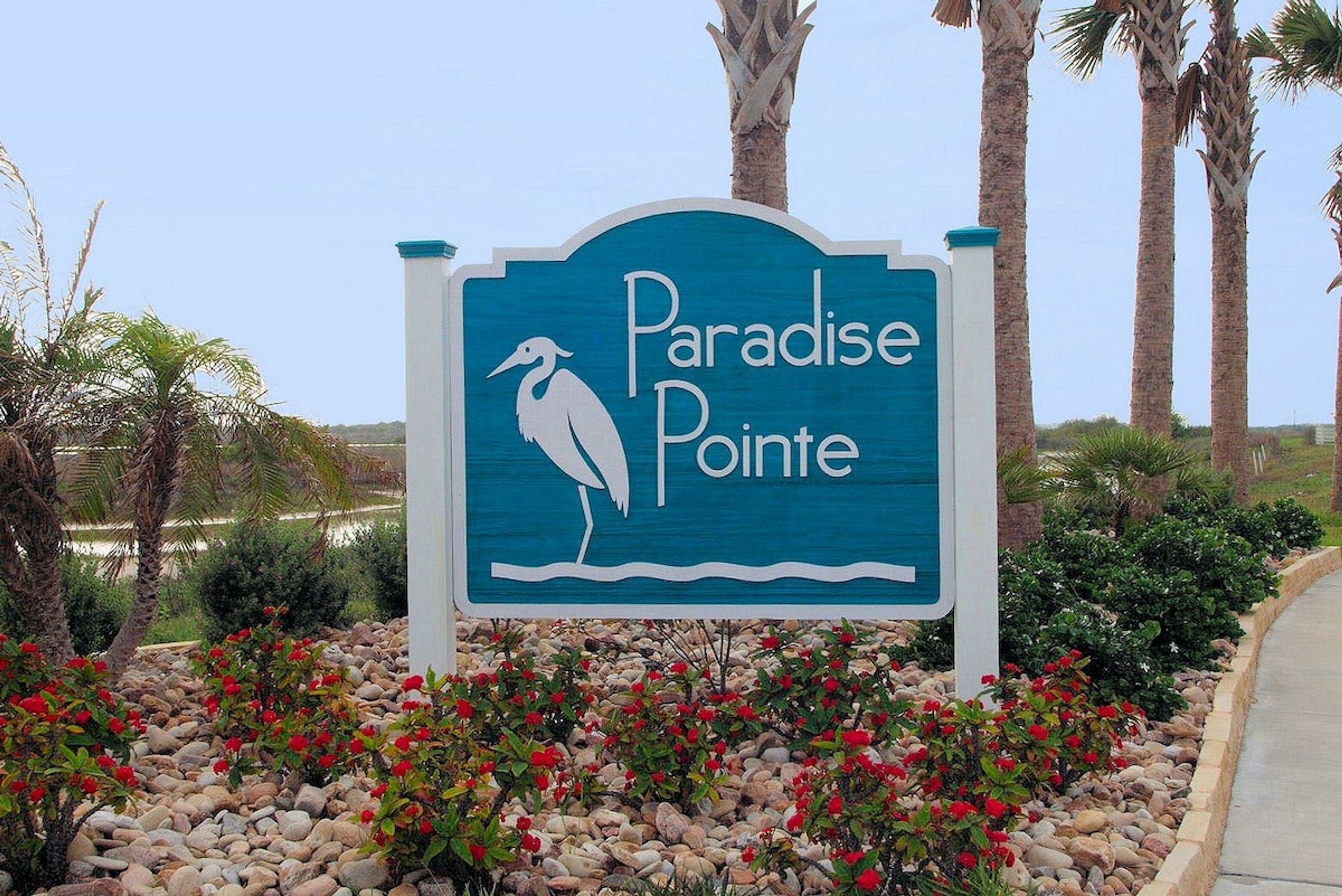 A sign for Paradise Pointe with a bird silhouette and a palm tree.