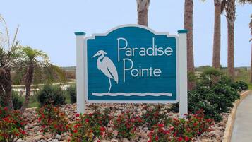 A sign for Paradise Pointe with a bird silhouette and a palm tree.