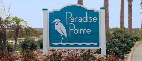 A sign for Paradise Pointe with a bird silhouette and a palm tree.