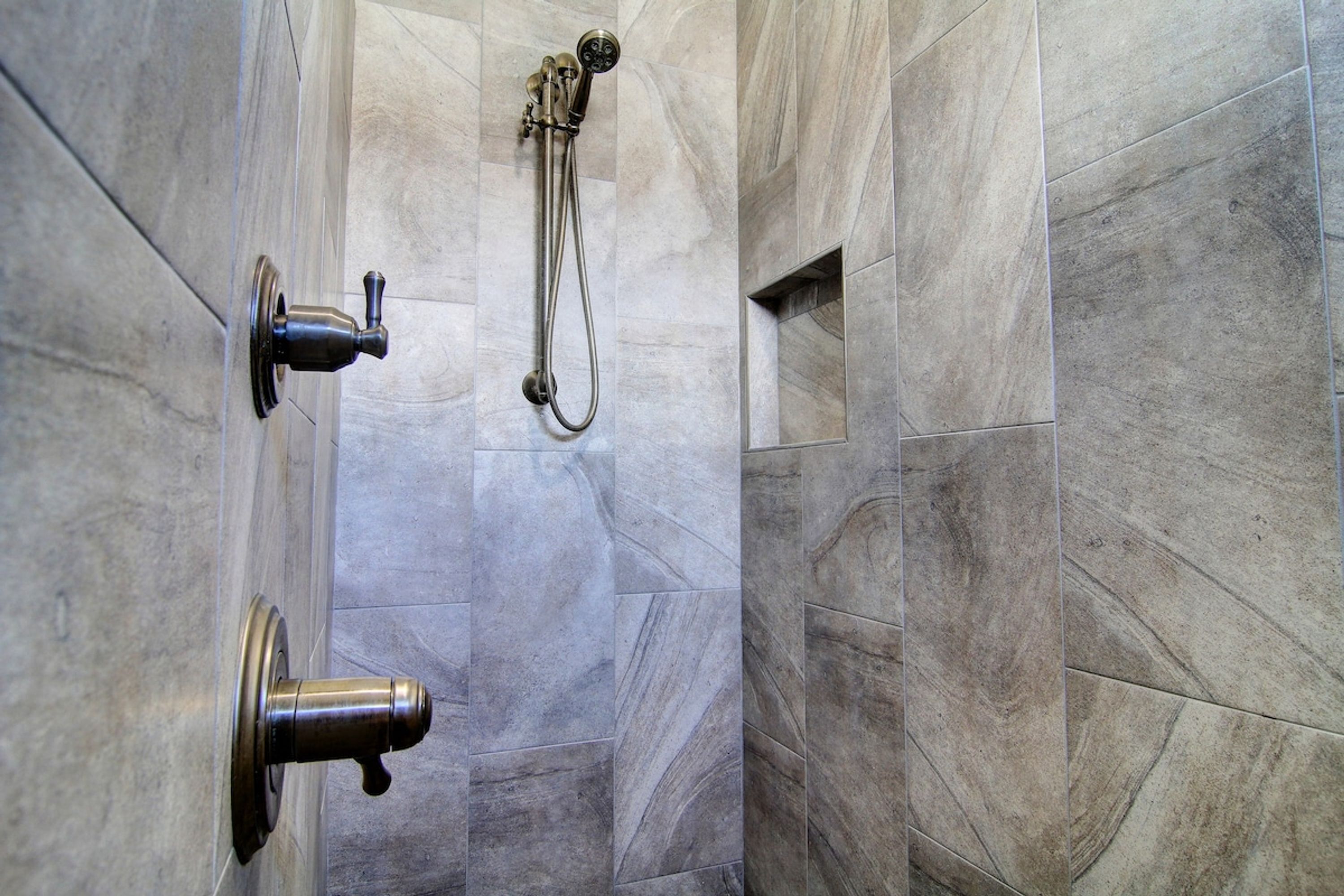 Ein Duschbereich mit Handbrause und am Wand montiertem Wasserhahn.