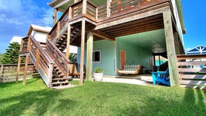Ein zweistöckiges Haus mit einer Holzterrasse und einer Treppe, die zum oberen Stockwerk führt.