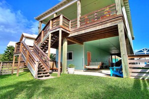 A two-story house with a wooden deck and a staircase leading to the upper level. - Salty Pelican - Family Friendly Community Pool (Port Aransas)