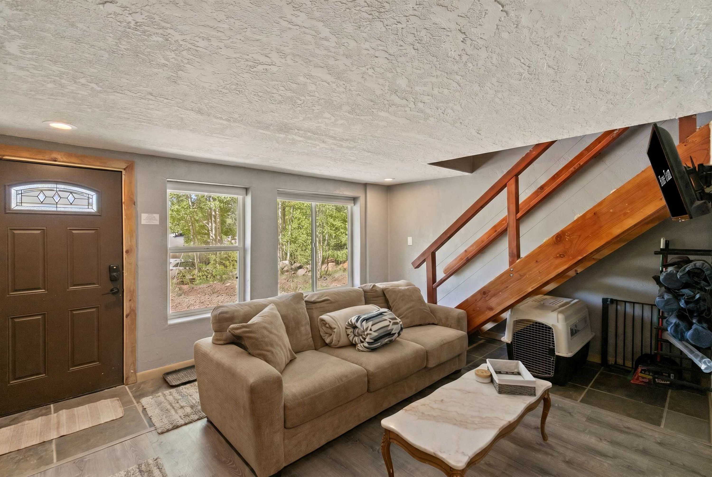 A cozy living room with a sofa, a coffee table, and a staircase.