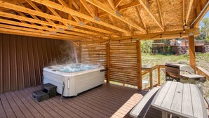 Un bain à remous installé sous une pergola en bois, avec une terrasse en bois et des meubles d’extérieur.