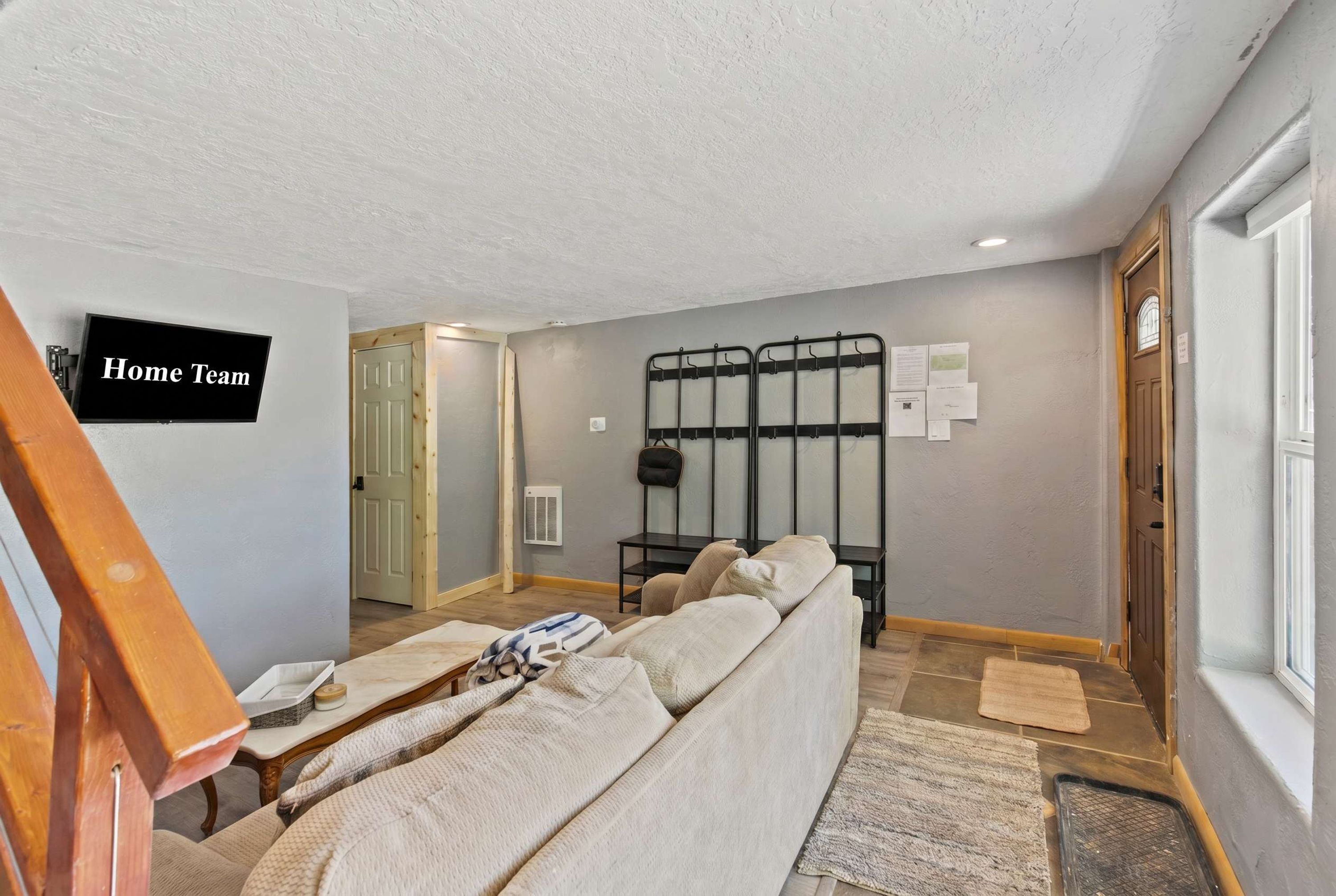 A compact living space with a sofa, a television, a metal rack, and a door leading to another room.