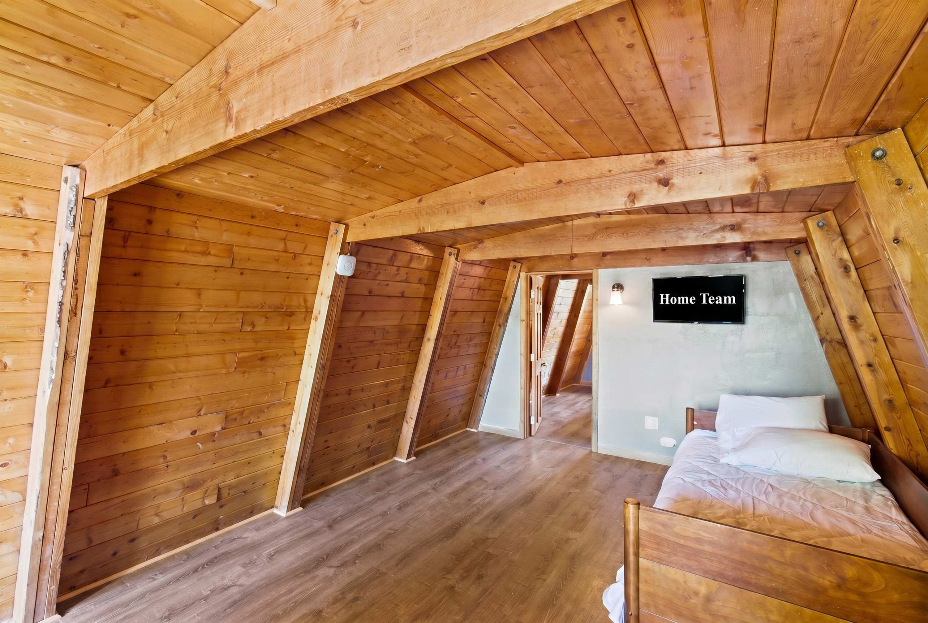 Ein Schlafzimmer im Dachgeschoss mit Holzboden, einem Flachbildfernseher und einem Schild mit der Aufschrift 'Home Team'.