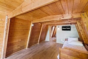 Un dormitorio en ático de madera con cama, televisor de pantalla plana y un letrero que dice 'Home Team'.