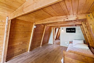 Un dormitorio en ático de madera con cama, televisor de pantalla plana y un letrero que dice 'Home Team'.