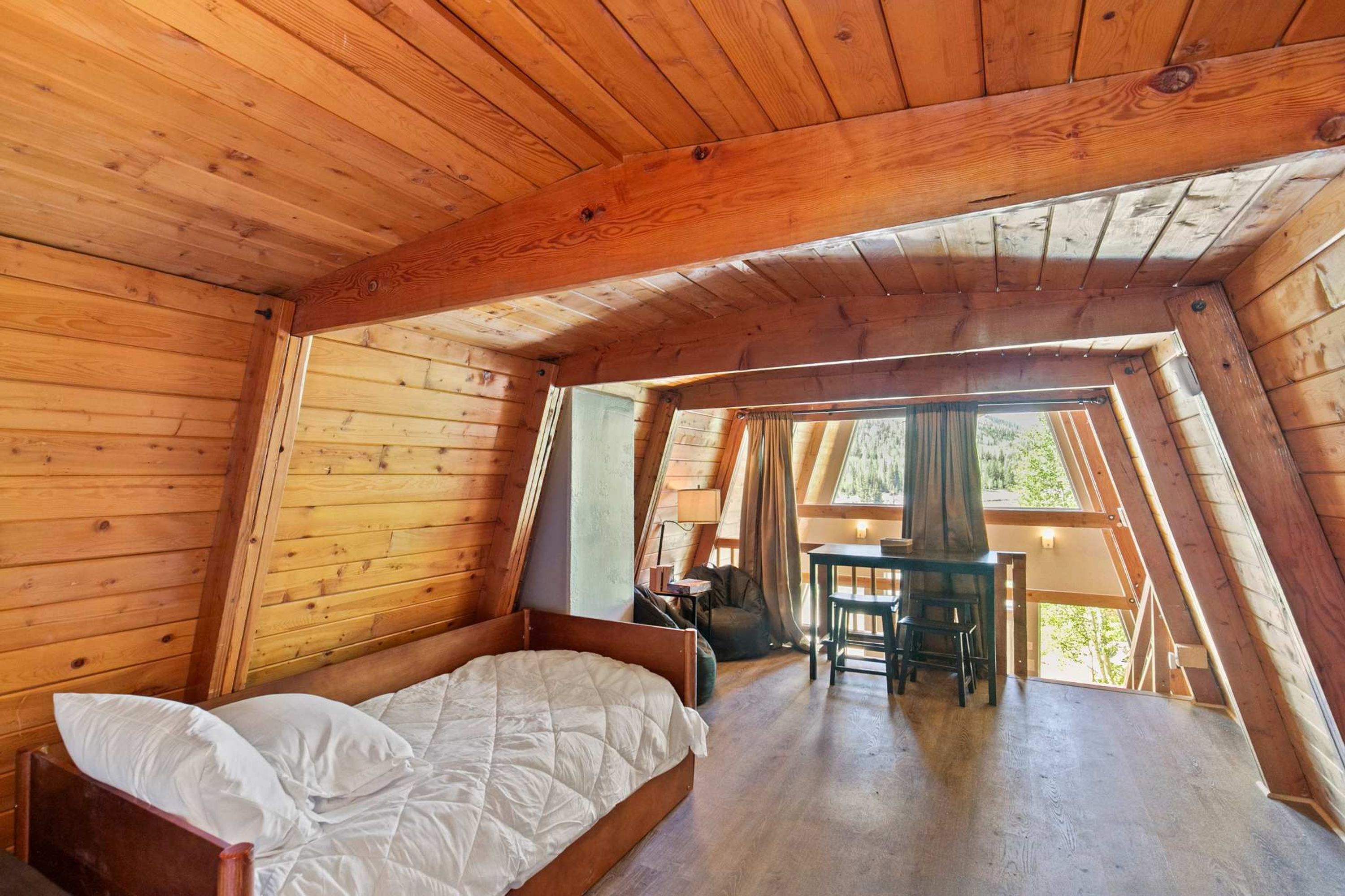 A wooden interior with a bed, a table, and a chair.