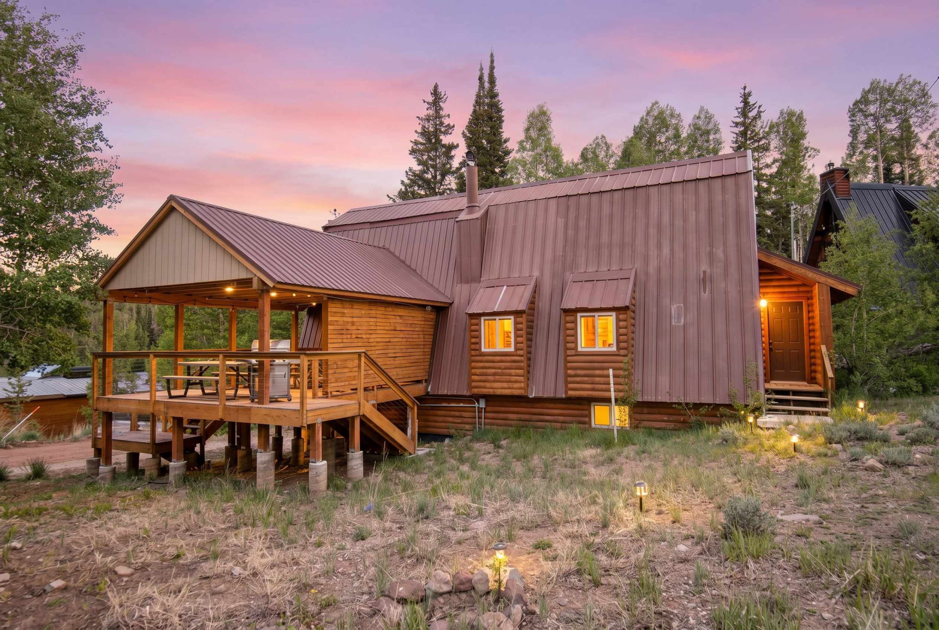 A rustic cabin with a deck, a covered porch, and a large wooden structure.