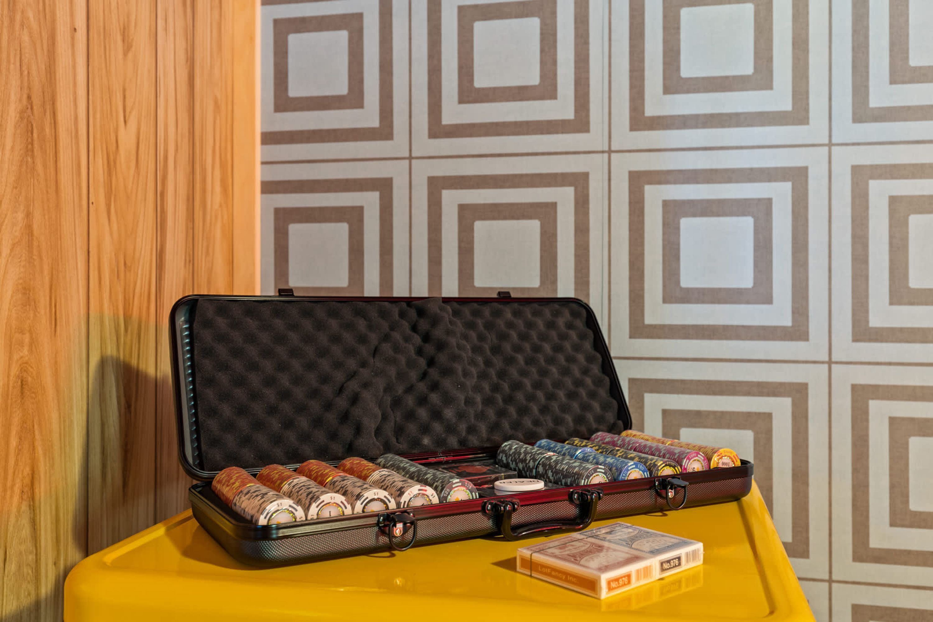 A suitcase with various items on a yellow surface against a patterned wall.