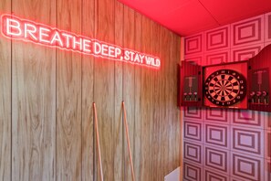 A dartboard mounted on a wall with a neon sign above it that reads 'BREATHE DEEP, STAY WILD'. - Lake Retreat Kayaks Theatre Hot Tub Sauna (Blue Ridge)