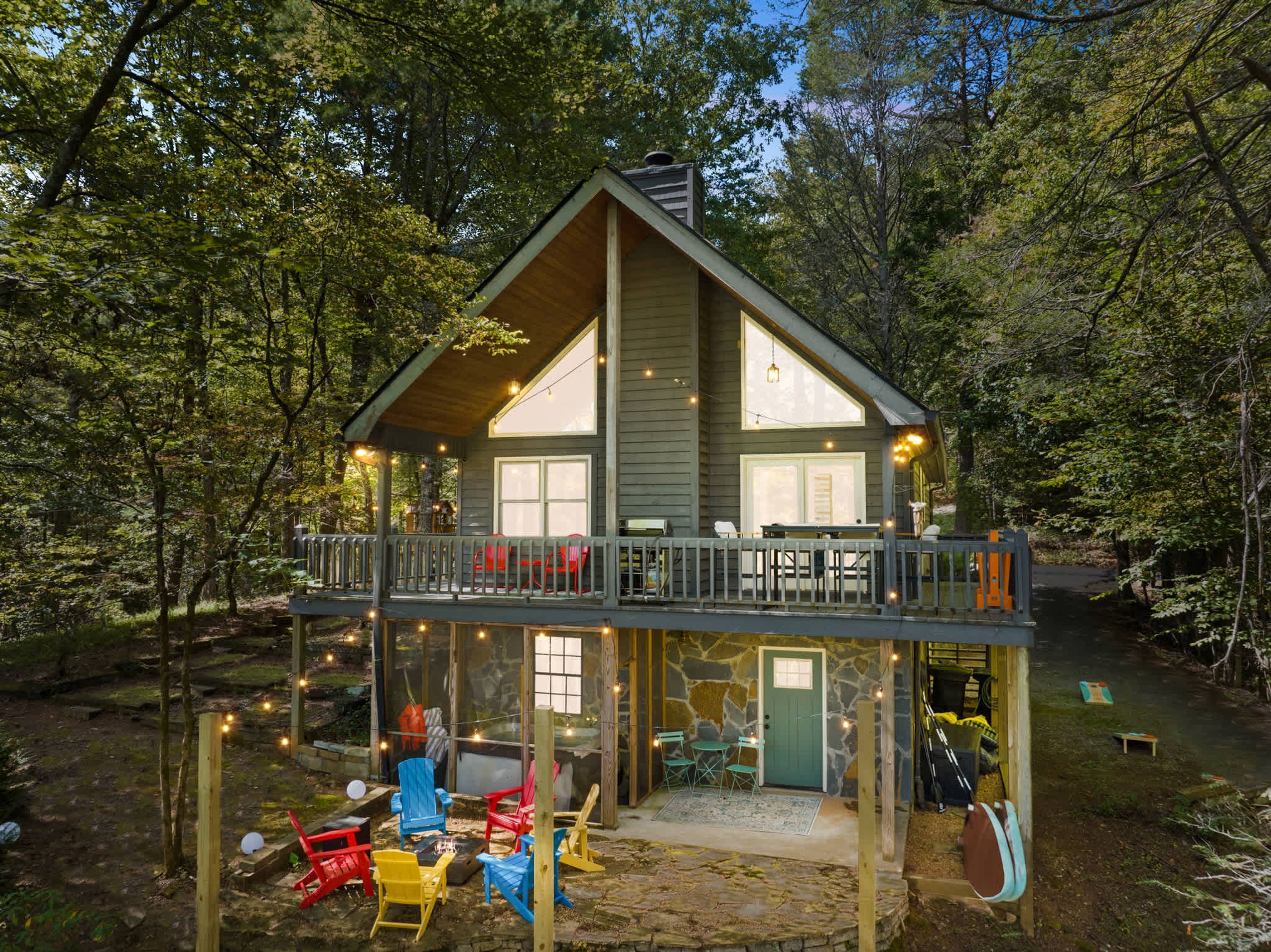 A cabin with a deck, outdoor seating, and a stone entrance.
