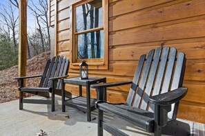 Une cabane en bois avec deux fauteuils Adirondack et une petite table sur laquelle est posée une lanterne.