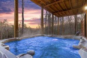 A hot tub with a view of a forest and a sunset.