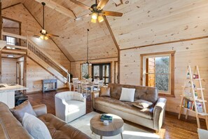 Ein geräumiger Wohnbereich mit hoher Decke, Holzwänden, einer Treppe und einem Essbereich.