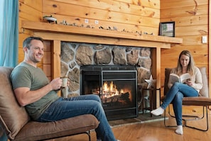 Ein gemütliches Zimmer mit Kamin aus Stein, Holzwänden und einer bequemen Sitzecke.