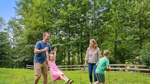 A family of four in a grassy outdoor area with trees and a wooden fence in the background. - Cozy Mountain Escape Hot Tub Fire Pit Views (Blue Ridge)