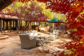An outdoor patio area with wicker furniture, a stone floor, and a fire pit. - Sedona Wellness Haven Sauna Gym Casita (Sedona)