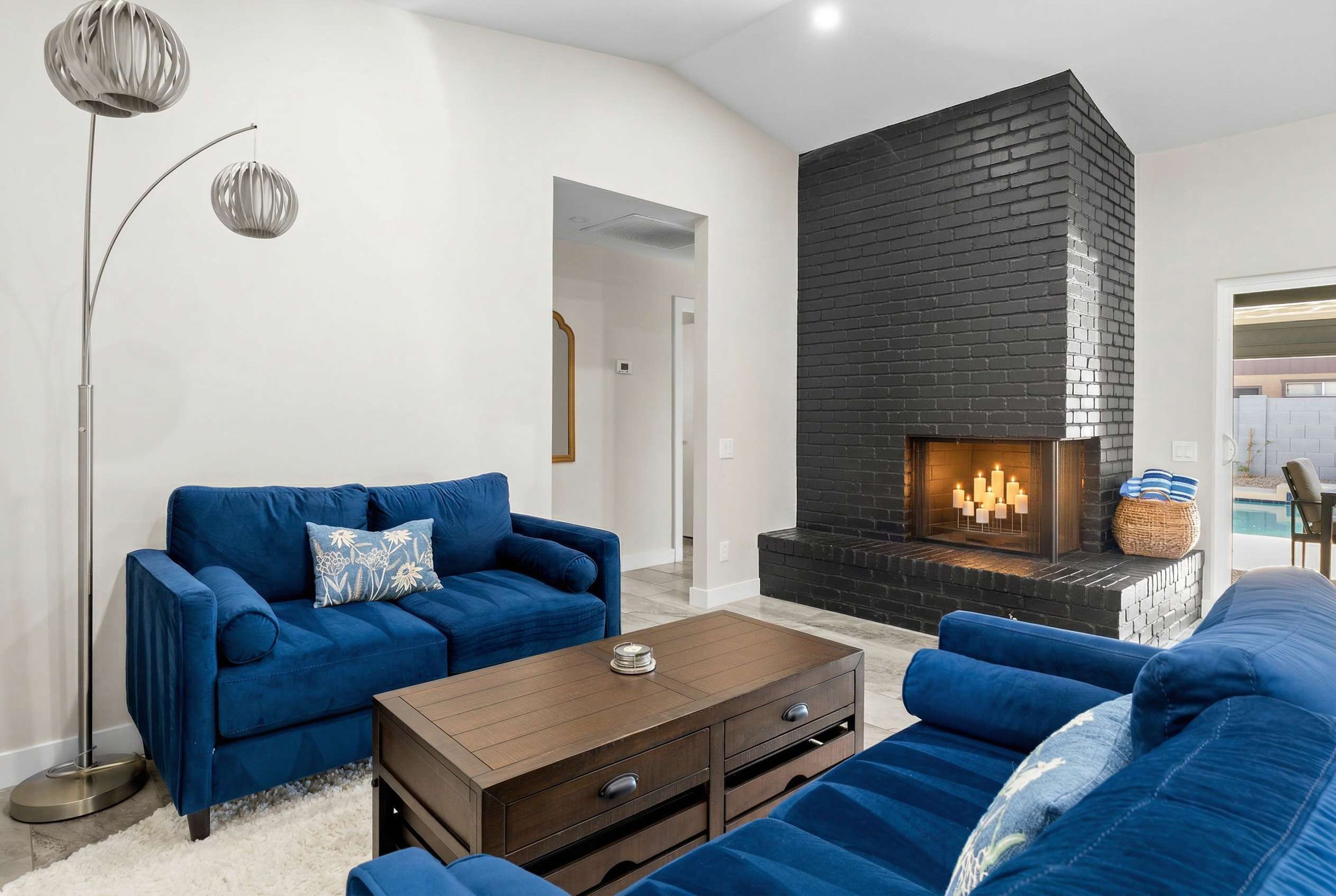 A modern living room with a fireplace, blue sofas, and a floor lamp.
