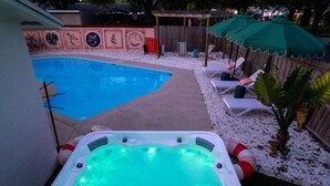 A backyard with a swimming pool, a hot tub, lounge chairs, and a wooden fence. - Resort Style Backyard Tiki Bar Renovated Pool (Largo)