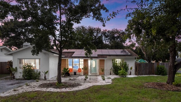 A single-story house with a front porch, a small garden, and a tree in the foreground. - Resort Style Backyard Tiki Bar Renovated Pool (Largo)